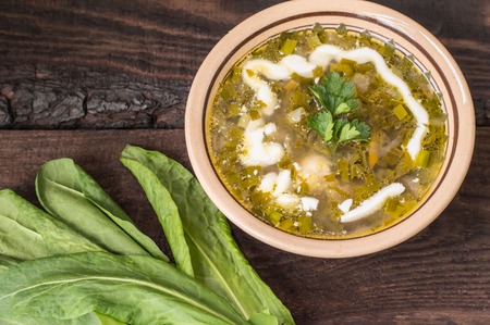 Green soup with sorrel, parsley and sour cream. Wooden background. Top view. Close-upの写真素材