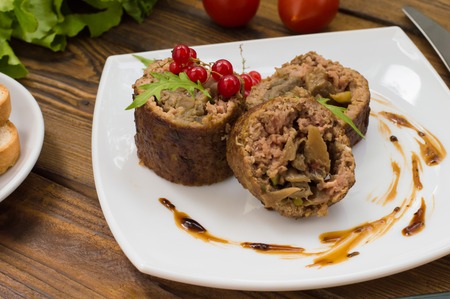 Meatloaf stuffed with mushrooms with sauce and berries. Wooden rustic background.