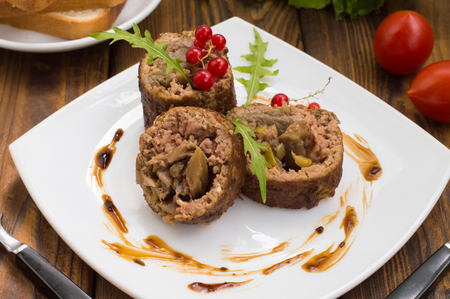Meatloaf stuffed with mushrooms with sauce and berries. Wooden rustic background.の写真素材