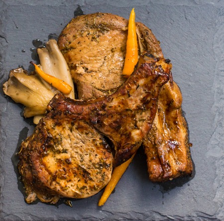 Pork steak on the bone grilled and oyster mushrooms, served on the stone