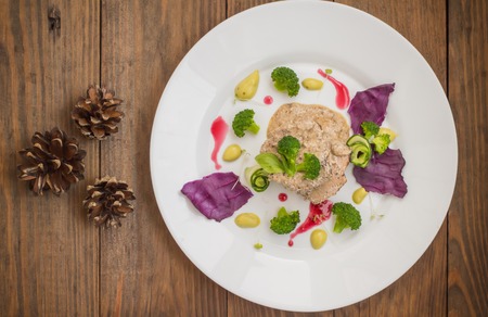 Pork medallions in cream sauce and micro greens on a white plate. Wooden background. Top view....