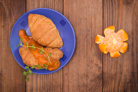 Orange jam and croissants for breakfast. Wooden background. Top viewの写真素材