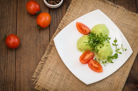 Georgian dumplings Khinkali of spinach dough with meat and tomato spicy sauce satsebeli on wooden background. Top view. Close-upの写真素材