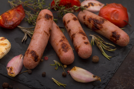 Grilled homemade rosemary sausages skewers. Kitchen table. Dark stone background. Top viewの写真素材