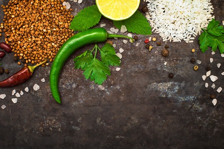Background with an assortment of different cereals, rice and buckwheat, lime and scented pepper and other spices on the background of old rusty iron. Close-upの写真素材