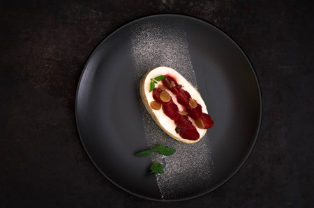Strawberry cake with almond petals. Old black background. Close-up. Top view. Close-upの写真素材
