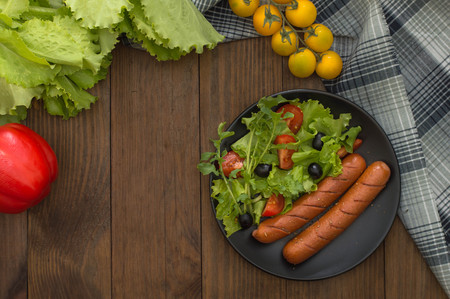 Grilled sausages and vegetables salad. Wooden background. Top view. Close-upの写真素材