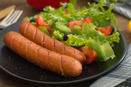 Grilled sausages and vegetables salad. Wooden background. Top view. Close-upの写真素材