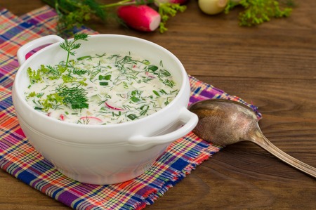 Okroshka. Summer light cold yogurt soup with cucumber, radish, eggs and dill on a wooden table. Wooden background. Close-up. Top viewの写真素材