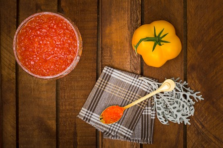 Red caviar in glass jar with gold spoon close up. Sea food. Healthy eating. Diet. Wooden rustic background. Selective focus. Top viewの写真素材