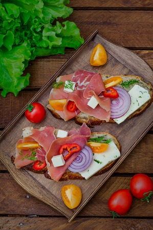 Ciabatta sandwich with salad leaves, jamon serrano and mozzarella. Wooden rustic background. Top view. Selective focusの写真素材