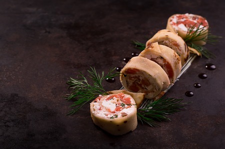 Rolls of thin pancakes with salmon, horseradish cream cheese. Black old background. Top view....