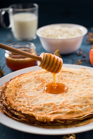 Fresh pancakes with honey, maple syrup, cottage cheese and tangerines. Wooden background. Top view. Selective focusの写真素材
