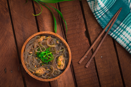 Japanese cuisine, soup with chashu pork, chives, sprouts, noodles and seaweed on the table under the sunlight. Wooden rustic background. Top view.の写真素材