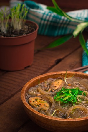 Japanese cuisine, soup with chashu pork, chives, sprouts, noodles and seaweed on the table under the sunlight. Wooden rustic background. Top viewの写真素材