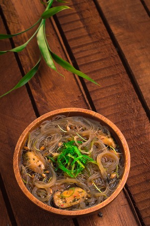 Japanese cuisine, soup with chashu pork, chives, sprouts, noodles and seaweed on the table under the sunlight. Wooden rustic background. Top viewの写真素材