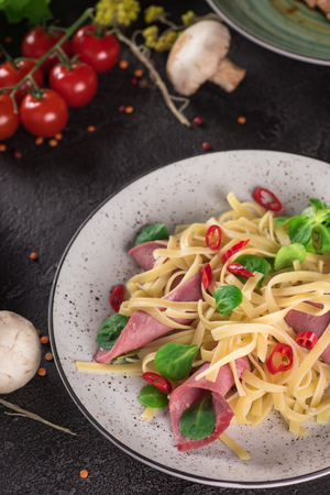 Italian spaghetti. Tagliatelle pasta with ham. Selective focus. Black background, Top viewの写真素材