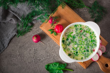Summer yoghurt cold soup with radish, cucumber, and dill on wooden table. Okroshka.の写真素材