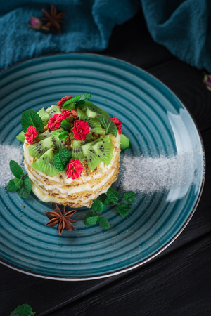 Delicious cake with fruit and mint decoration on black background.の写真素材