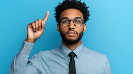 African american man in eyeglasses pointing up on blue backgroundの素材