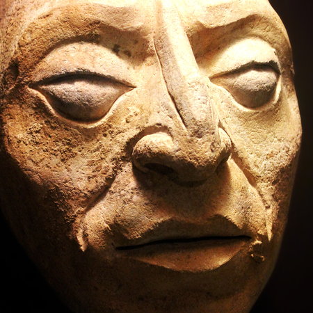 Ancient sculpted stone face gazing with supernatural eyesの写真素材