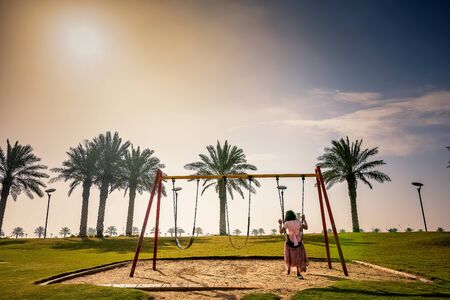 Happy child girl on swing in winter season Modon lake Dammam Saudi Arabia.の写真素材