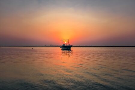 Beautiful Sunrise Boat in seaside with red and dark sky. Dammam -Saudi Arabiaの写真素材