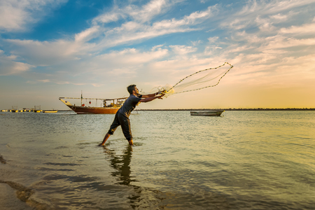 Silhouettes of the fishermen throwing fishing net during sunset in Dammam seaside Saudi Arabiaのeditorial素材