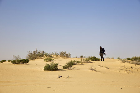 A young man walking in the desert of Dubai, United Arab Emiratesの写真素材