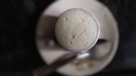 Foam bubbles on top of cup full of milk in dark backgroundの写真素材