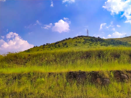 Electric tower on top of stepped mountain with vertical grass.の写真素材
