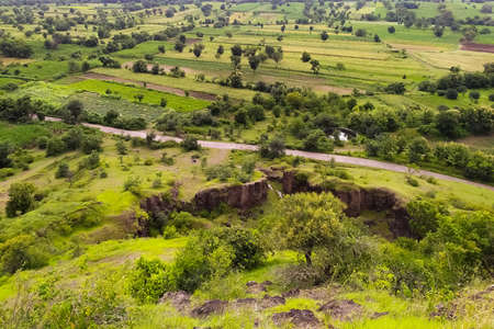 Road passing through excavated mine green farmlandの写真素材