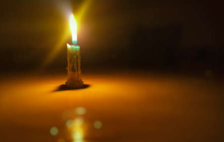 Burning orange flame with candlestick in darknessの写真素材