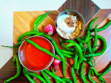 Thai spicy sauce in bowl with chilli and garlic on wooden tableの写真素材