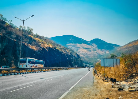 Vehicles on Road highway travelling journey to the destination and signboard facing to the huge mountain rangeの写真素材