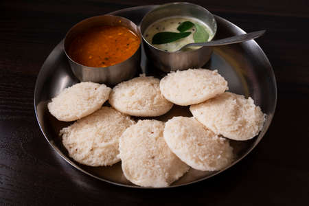 a lower angle view of south karnataka homemade rave idly, sambar & chutney isolated on wooden table