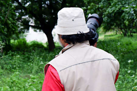 a closeup backside view of young professional photographer holding camera picture