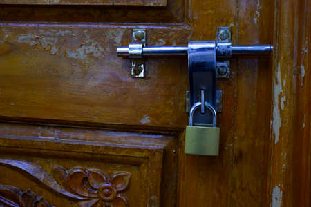 a close shot of locked padlock isolated on wooden doorの写真素材