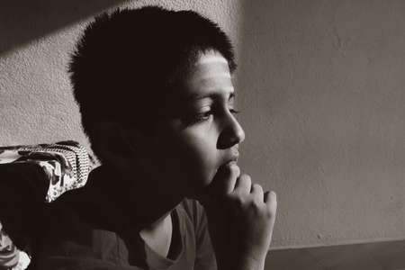 a close head shot of Indian boy thinking low key light in the morning monochrome photo, Kalaburagi, Karnataka/India-October 09 2020のeditorial素材