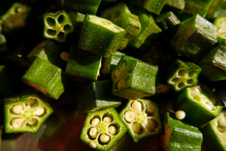 a closeup view of fresh green lady finger pieces isolated on panの写真素材