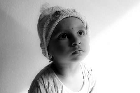 a close shot of Indian girl child wearing cap & looking upside in the sunlight monochrome photo, Kalaburagi, Karnataka/India-October 18.2020のeditorial素材