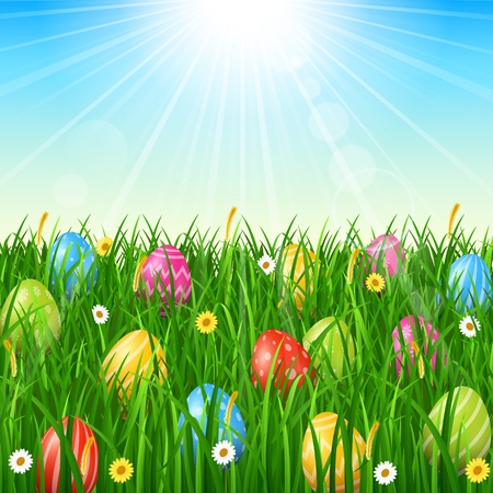 Easter background with easter eggs in the grass on sunny sky backgroundの写真素材