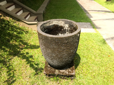 trash can made of concrete and with a green grass background and shadows of leavesの写真素材