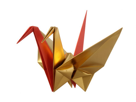 Two origami cranes, one gold and one red, are positioned together against a white background.の素材