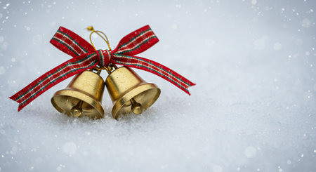 Christmas bells with red ribbon on snow background with bokeh effectの素材
