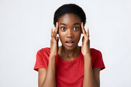Shocked african american woman in red t-shirt on white backgroundの素材