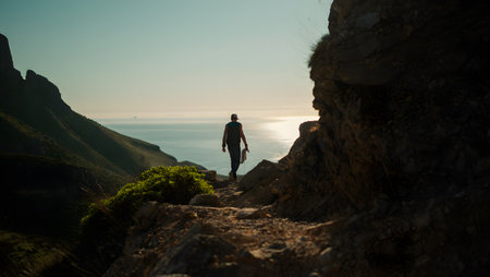 Hiker standing on the edge of a cliff and looking at the seaの素材