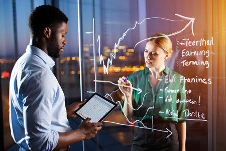 business, education, statistics and people concept - smiling businesswoman and businessman with tablet pc computer over city backgroundの素材
