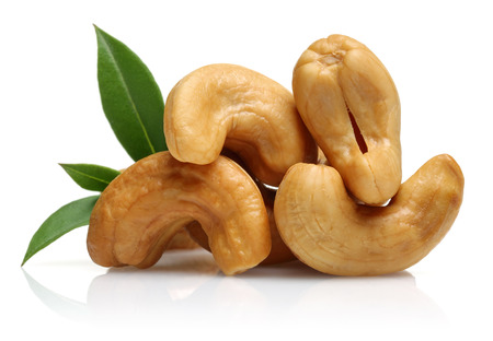 Roasted cashew nuts with green leaves isolated on white backgroundの写真素材