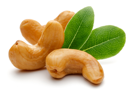 Roasted cashew nuts with green leaves isolated on white backgroundの写真素材